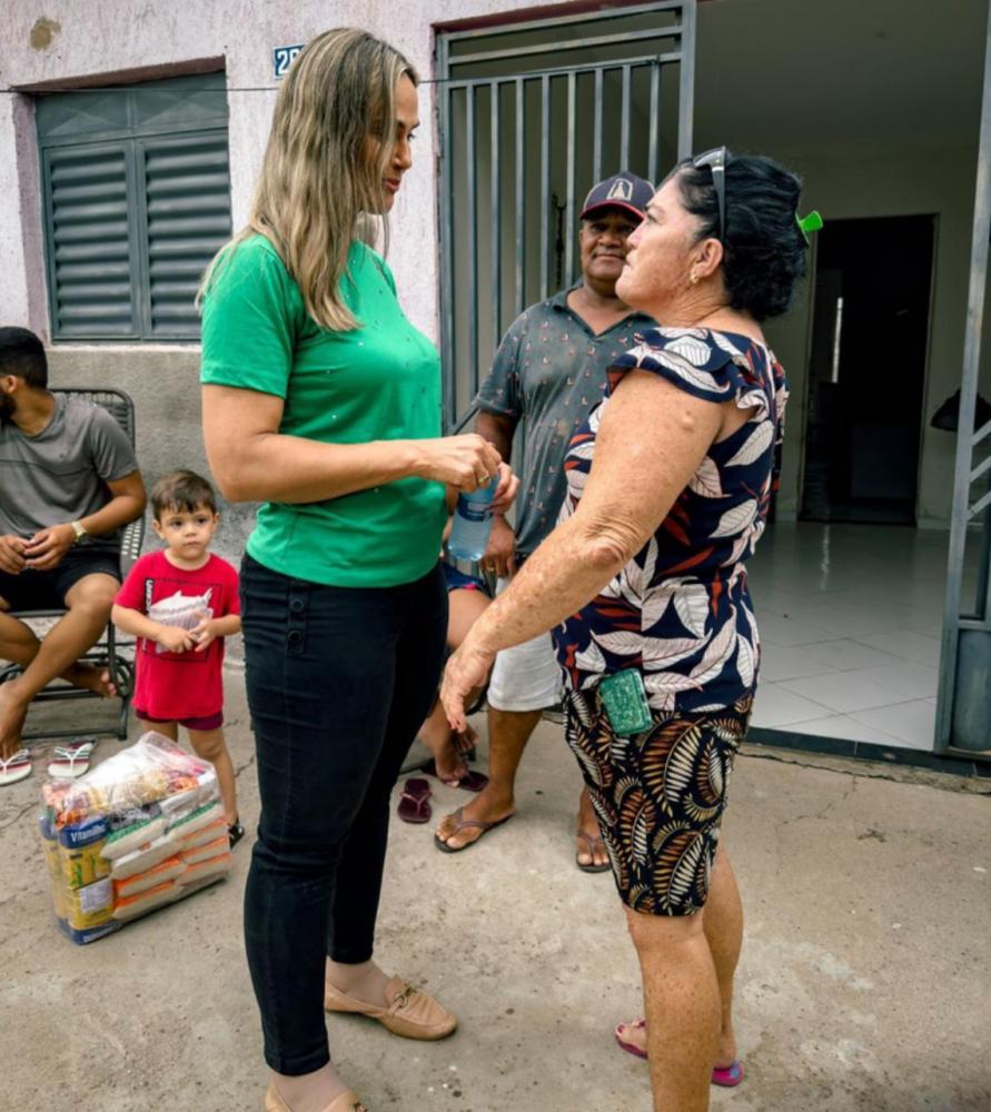 Maria Elizete conversa com uma dona de casa e entrega a cesta 